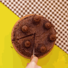 a person is cutting a piece of chocolate cake