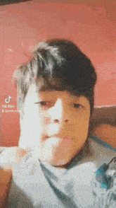 a young boy is making a funny face and looking at the camera while laying on a bed .