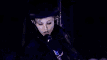 a woman wearing a top hat and headphones is looking down .