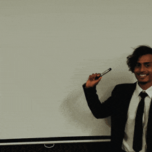 a man in a suit and tie points to a white board that says use your
