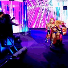a woman is standing on a stage in front of a crowd holding a sword .