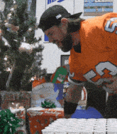 a man wearing an orange jersey with the number 23 on it is standing in front of a christmas tree