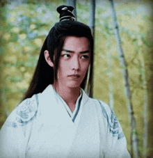a young man with long black hair is wearing a white robe