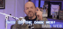 a man is sitting in front of a microphone with the words " this is the dark web " on the screen behind him .