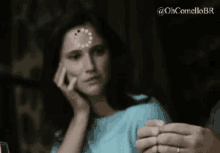 a woman with a star on her forehead is sitting at a table with a man clapping her hands .