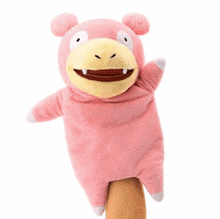 a pink stuffed animal with a yellow face is on a finger