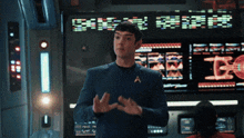 a man in a star trek uniform is standing in front of a large screen that says " see "
