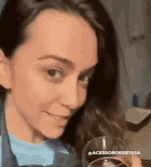 a woman in a blue shirt is holding a glass of wine .