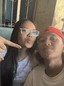 a boy and a girl are posing for a picture and the girl is pointing at the boy 's face
