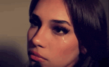 a woman is crying with a tear running down her face .