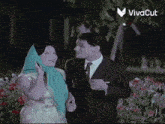 a man and a woman are standing next to each other in front of a sign that says viva cut
