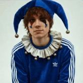 a man wearing a blue adidas jacket and a blue jester hat