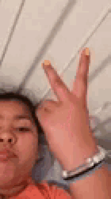 a woman is making a peace sign with her fingers .