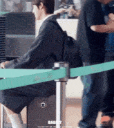 a man with a backpack sits on a suitcase in front of a green tape that says rabbit
