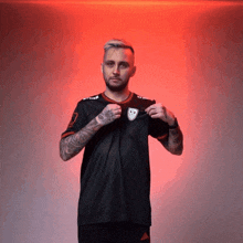 a man with a tattoo on his arm is wearing a black adidas shirt