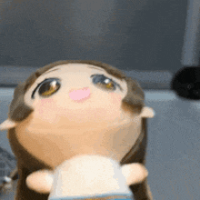 a stuffed doll with long brown hair is sitting on a table and looking up .