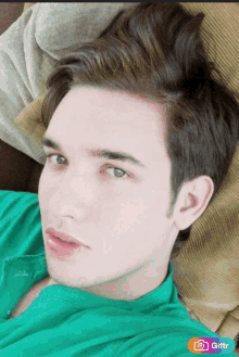 a young man in a green shirt is laying on a couch with a giftr sticker on the bottom right