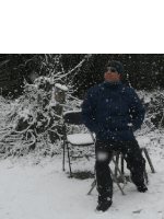 a man in a blue jacket is sitting in a chair in the snow