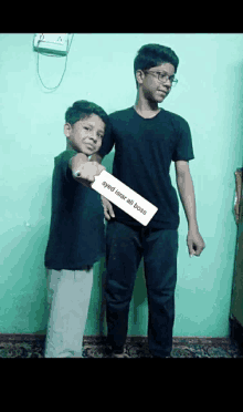 two young boys standing next to each other with one holding a card that says eyed isnar ali boss