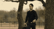 a man in a black sweater is holding a black bag