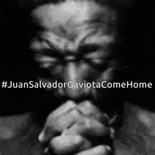 a black and white photo of a man praying with his hands folded in prayer .