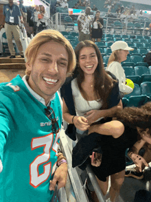 a man in a miami dolphins jersey poses for a photo with a woman