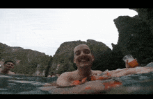 a man in the water with a glass of orange juice in his hand