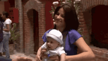 a woman is holding a baby in her arms and the baby is wearing a white hat
