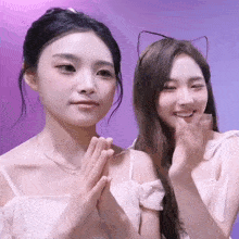 two girls are posing for a picture and one has cat ears on