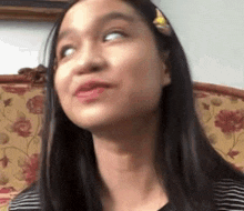 a young girl is sitting on a couch with her eyes closed and making a funny face .