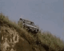 a car is driving down a grassy hillside .