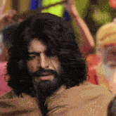 a man with long hair and a beard is looking at the camera