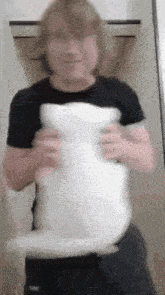 a man in a black shirt is holding a white stuffed animal .