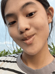 a close up of a person 's face with a striped shirt on
