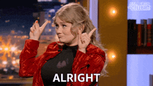 a woman in a red jacket says alright in front of a smarter than celebrity logo