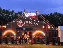 a group of people standing in front of a circus tent called zirkus nemo