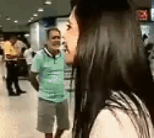 a woman with long hair is standing next to a man in a green shirt and shorts .