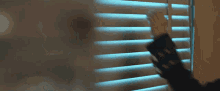 a woman in a black jacket is looking out of a window through blinds .