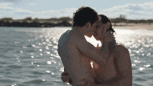 a man and woman kissing in the water on a beach