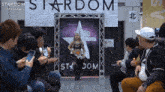 a group of people sitting in front of a stardom sign