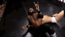 a wrestler is giving a horns sign while laying on the ground