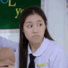 a girl in a school uniform and tie is making a face
