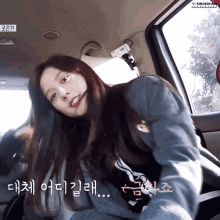 a woman sitting in a car with korean writing on the side