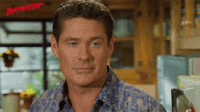 a man in a blue shirt stands in front of a sign that says baywatch