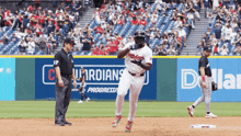 a baseball player wearing a white indians jersey runs to first base