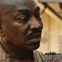a close up of a man 's face with a trap city logo in the corner