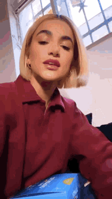 a woman in a red shirt is sitting on a couch with a box of tissues .