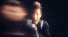 a blurry picture of a man in a suit and tie holding a sword in a dark room .