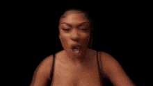 a woman in a black bra is making a funny face with her hands .