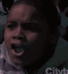 a young boy is making a surprised face while sitting in a crowd .